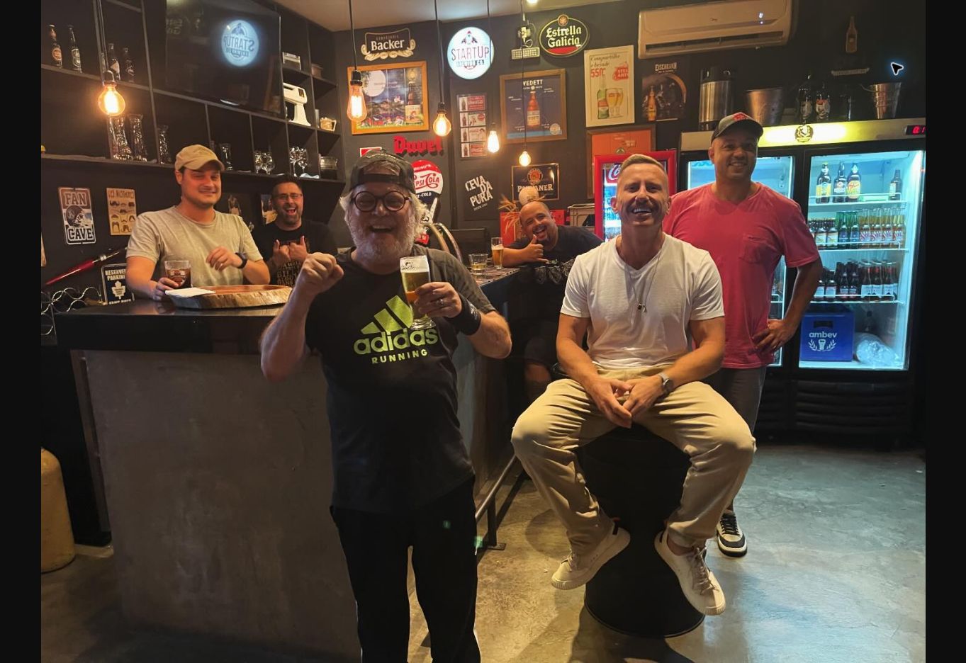 Clientes reunidos e sorrindo no bar da Barbearia Comendador